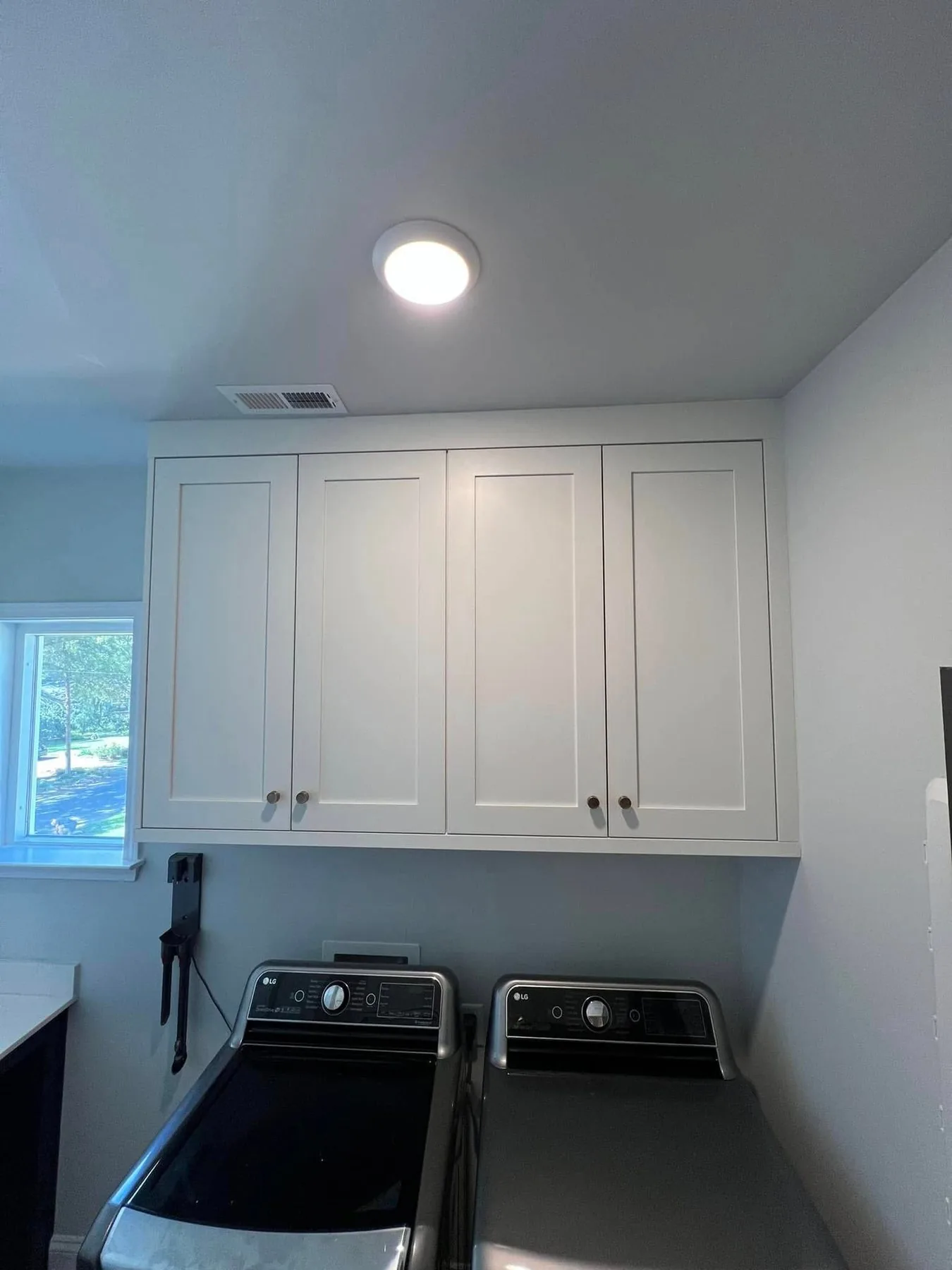 Custom white laundry room cabinetry above a washer and dryer