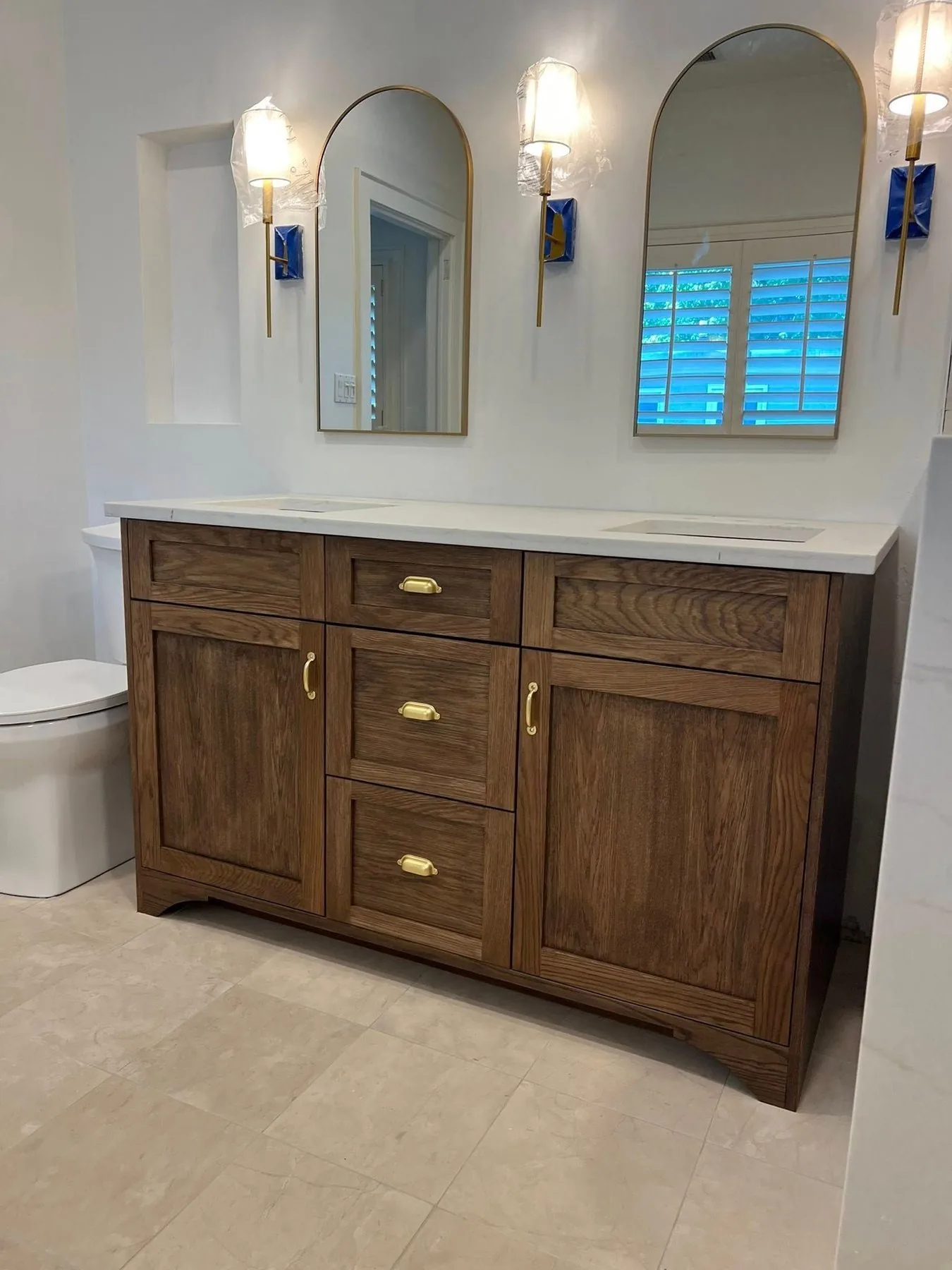 Stained walnut bathroom vanity with arched mirrors
